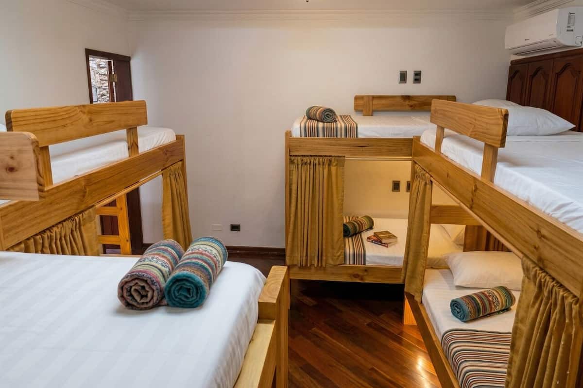 Una habitación con literas, suelo de madera y una ventana.