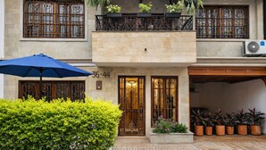 A two-story building with a balcony, a blue umbrella, and potted plants.