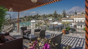 An outdoor patio with wicker furniture, a pergola, and a view of a mountain. - Maison du Soleil (Arequipa)