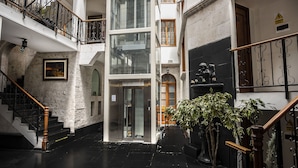 A multi-level interior with a staircase, a glass elevator, and a statue. - Maison du Soleil (Arequipa)
