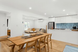 A modern kitchen with white cabinets, a stainless steel refrigerator, and a blue tiled backsplash.