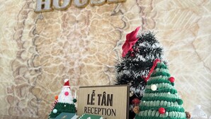 Un comptoir d’accueil avec une pancarte indiquant « Réception Lê Tân » et une décoration de Noël.