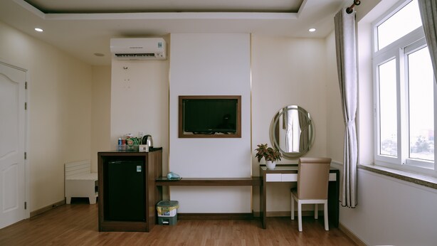 Une chambre d’hôtel avec un lit, un bureau, une chaise, une télévision et une fenêtre.