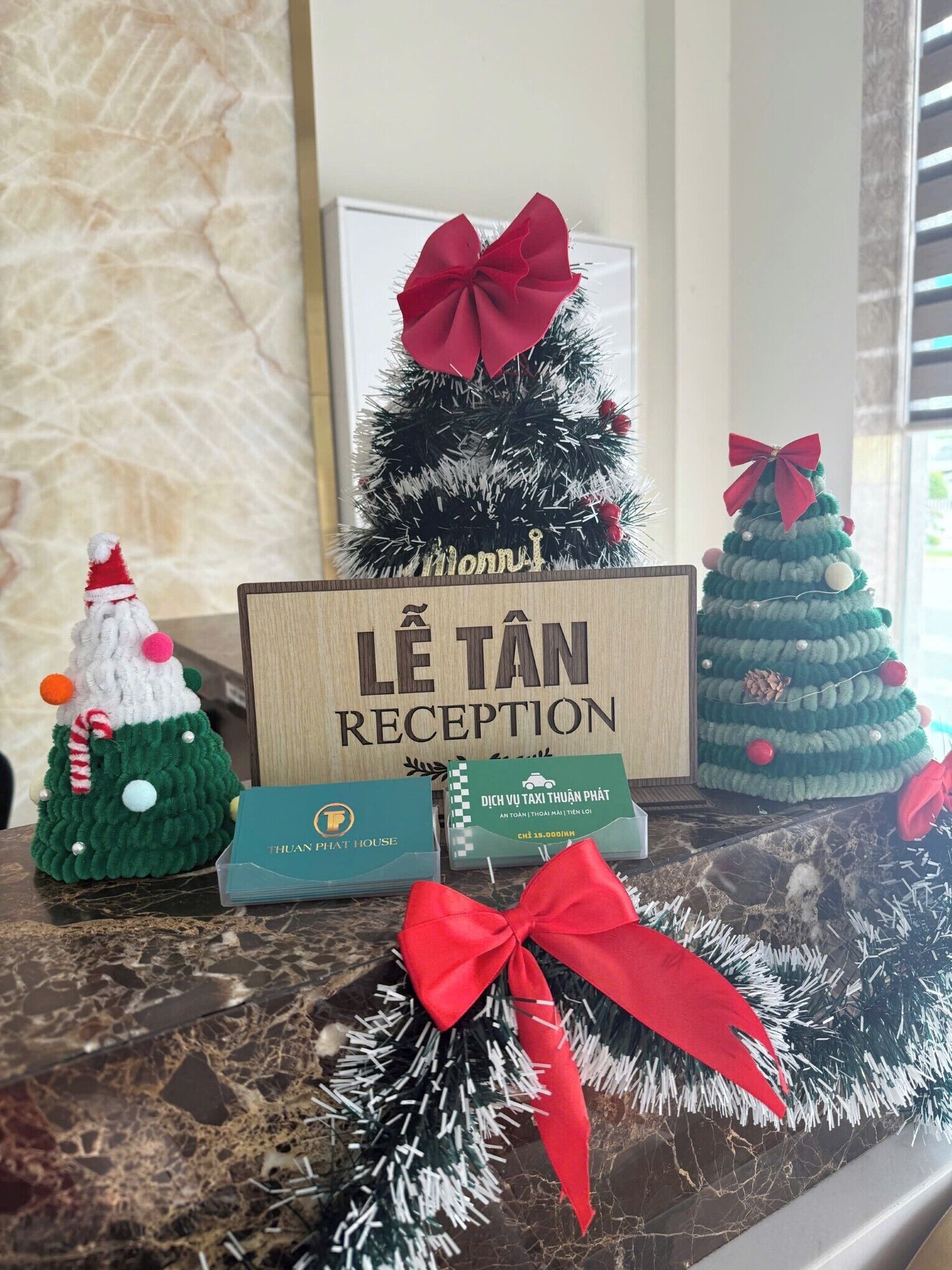A reception desk with a sign reading "LE TAN RECEPTION" and a Christmas tree with a red bow.