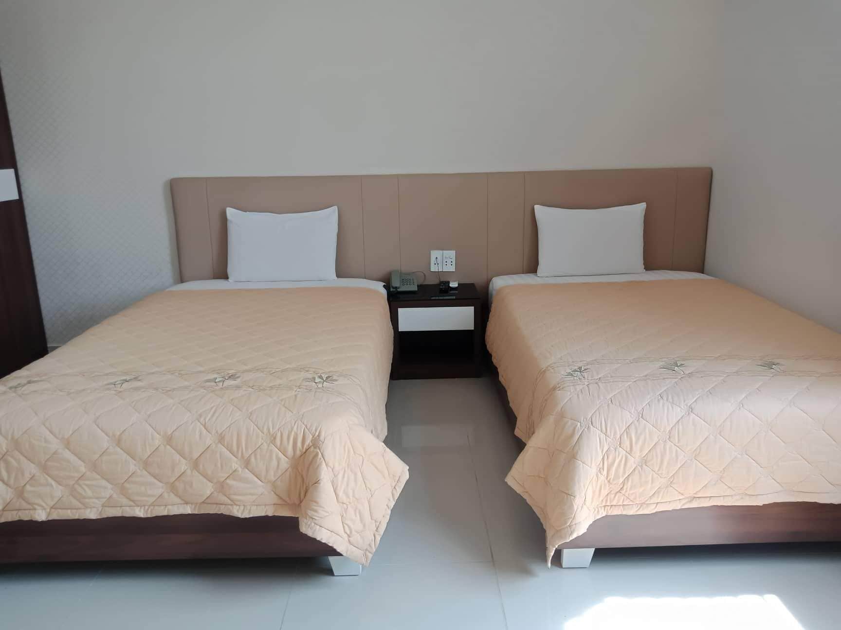 A double room with two beds, each with a headboard, a nightstand, and a phone.