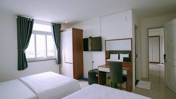 A hotel room with two beds, a desk, a chair, a TV, and a wardrobe.