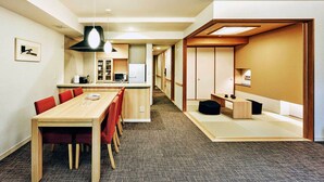 A modern interior with a wooden dining table, red chairs, a kitchen area, and a traditional Japanese room with tatami flooring.