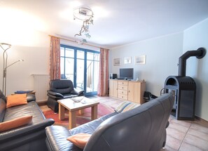 Una sala de estar con sofá, mesa de centro, televisor, mueble y chimenea.