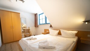 Un dormitorio con una cama grande, un armario de madera y una silla.