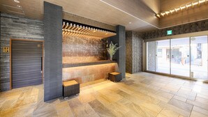 Un área de recepción con pared de piedra, techo de listones de madera y un gran puerta corredera.