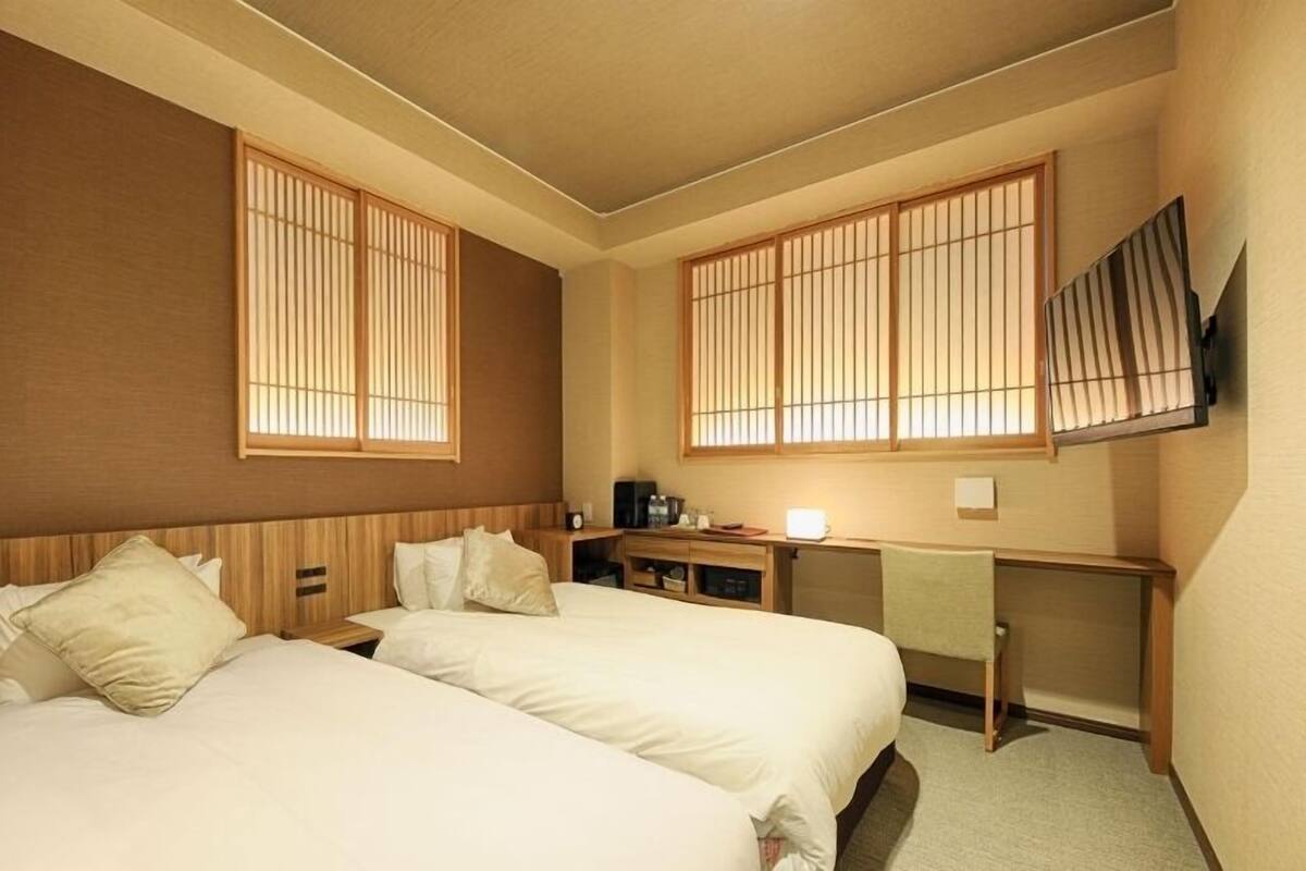 Habitación de hotel con dos camas, un escritorio y un televisor.