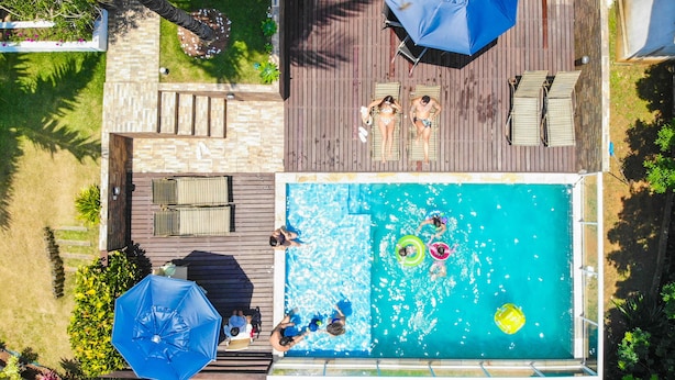 A rooftop pool with a wooden deck, lounge chairs, and umbrellas. - Pousada Villa Casablanca (Búzios)
