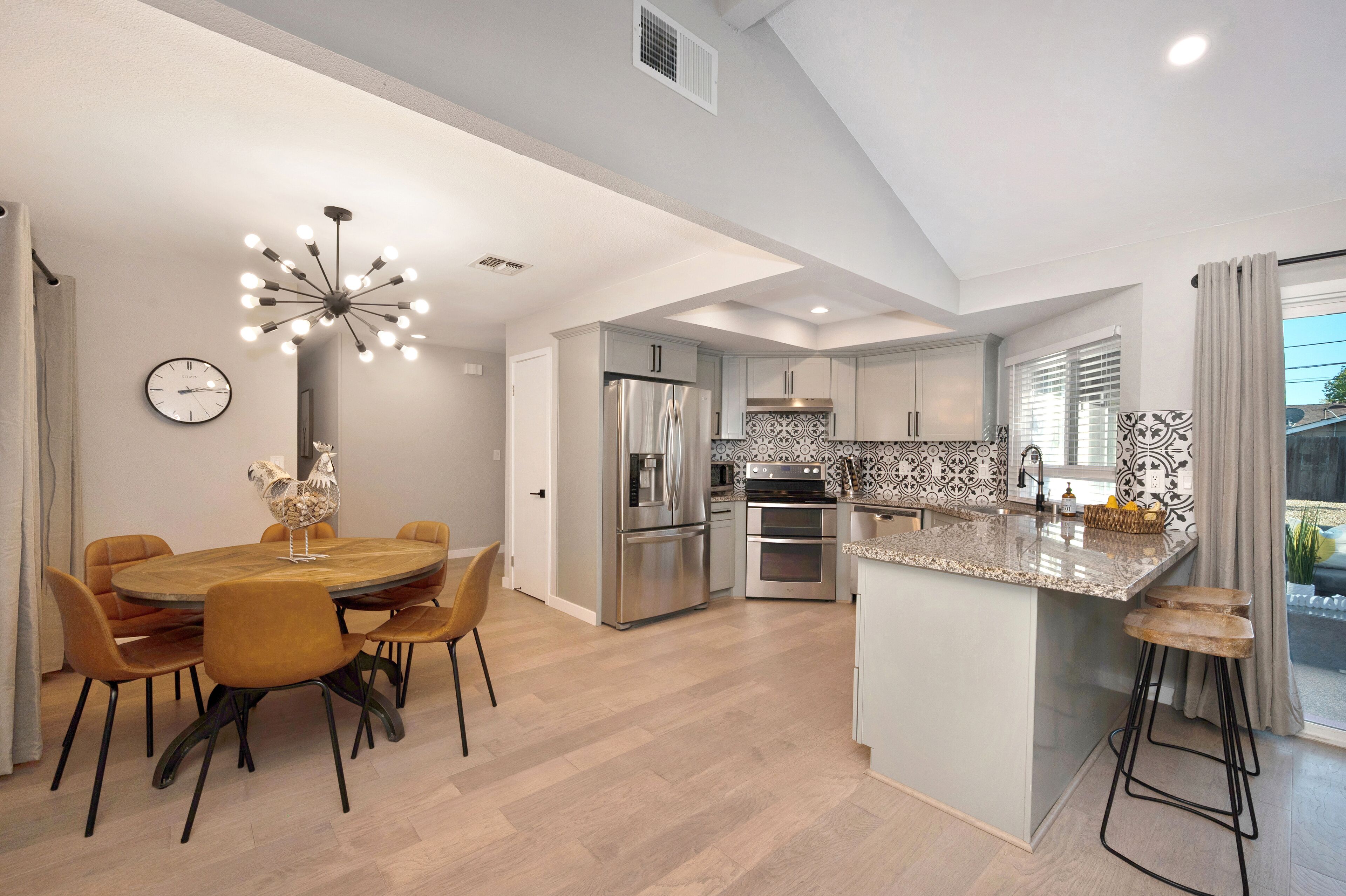 A modern kitchen with a central island, stainless steel appliances, and a dining area with a round table and chairs.