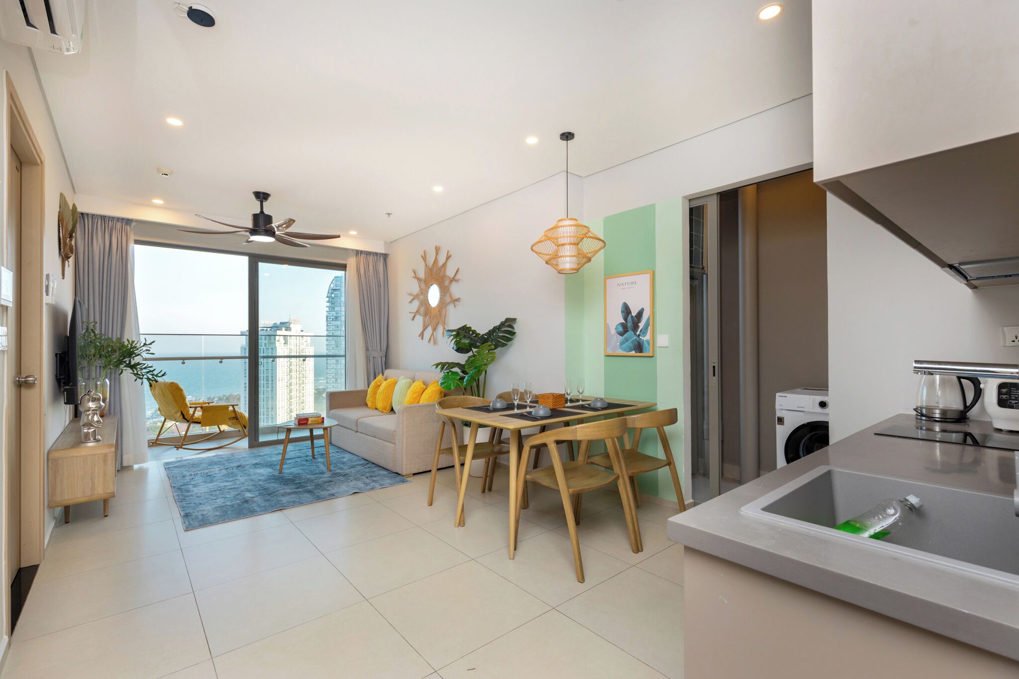 A modern living room with a dining area, a kitchen, and a balcony with a city view.