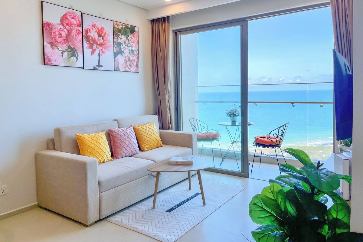 Una sala de estar moderna con un sofá, una mesa de centro y vista al mar a través de amplios ventanales.