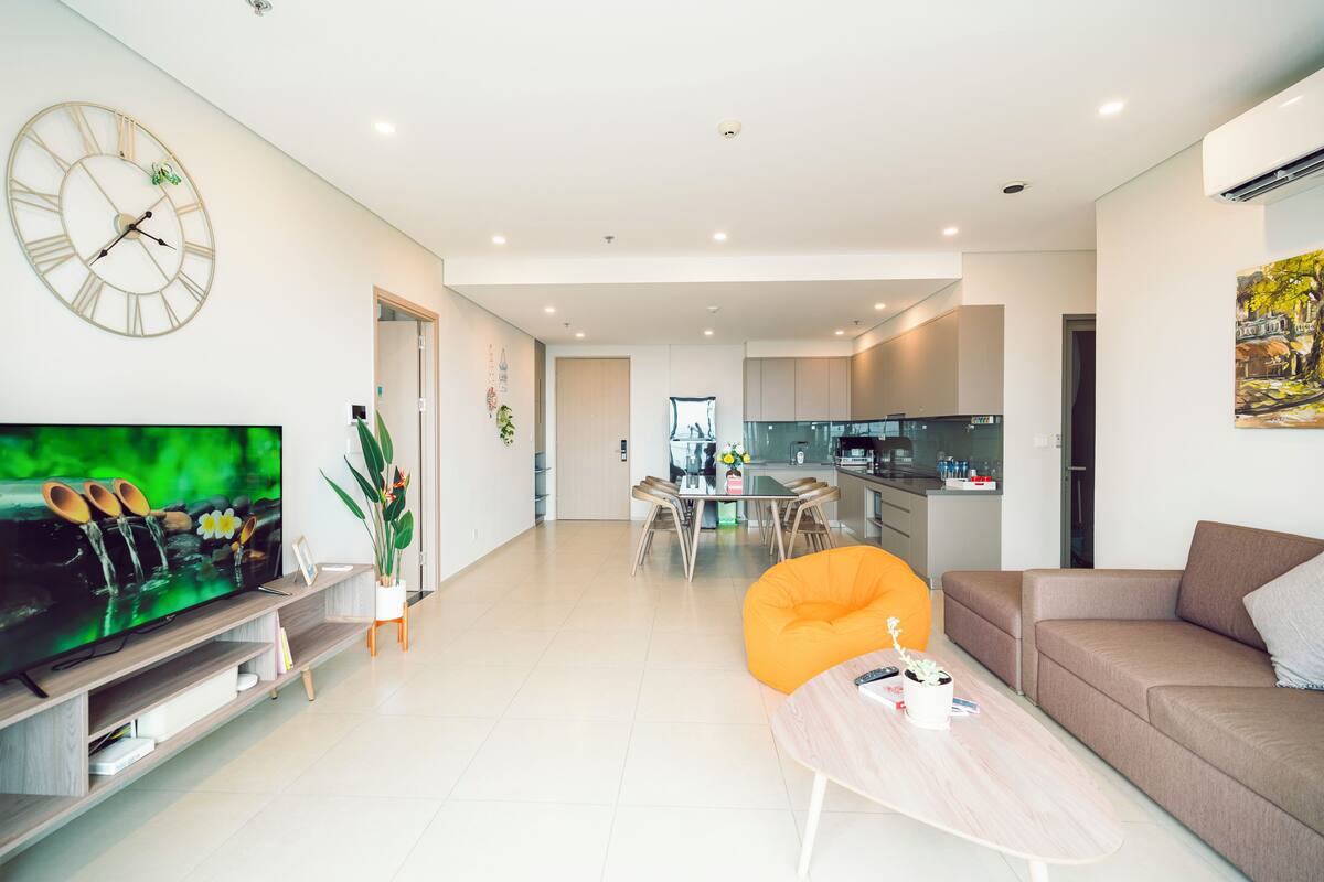 Una sala de estar moderna con una televisión de pantalla plana, un sofá, una mesa de centro y un comedor con una mesa y sillas.