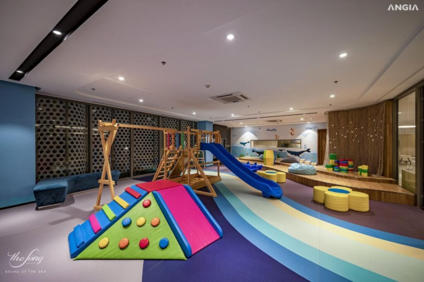 Zona de juegos infantiles con tobogán, pared de escalar y alfombras acolchadas.