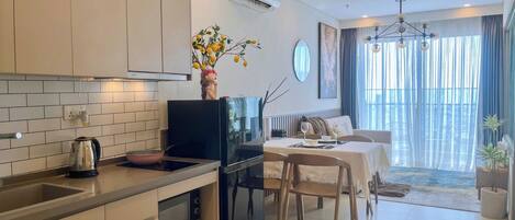 A modern kitchen with a dining area, featuring a refrigerator, microwave, and a vase with flowers.