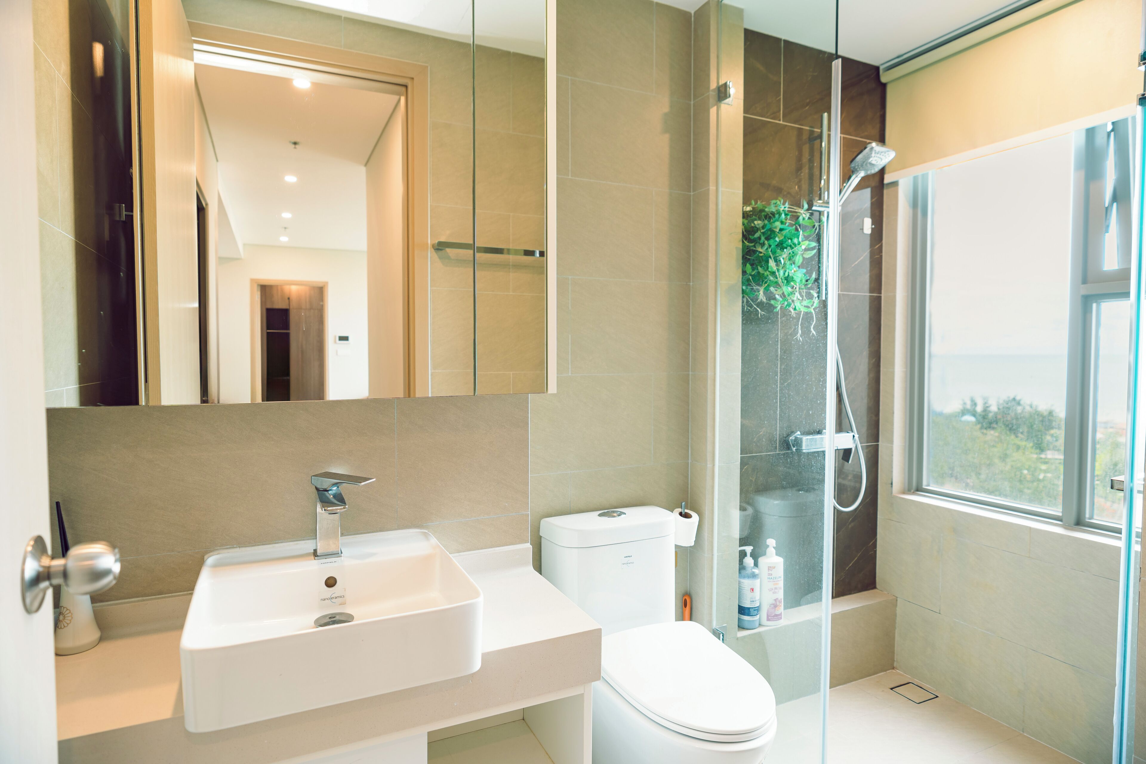 A modern bathroom with a glass-enclosed shower, a white sink, and a toilet.