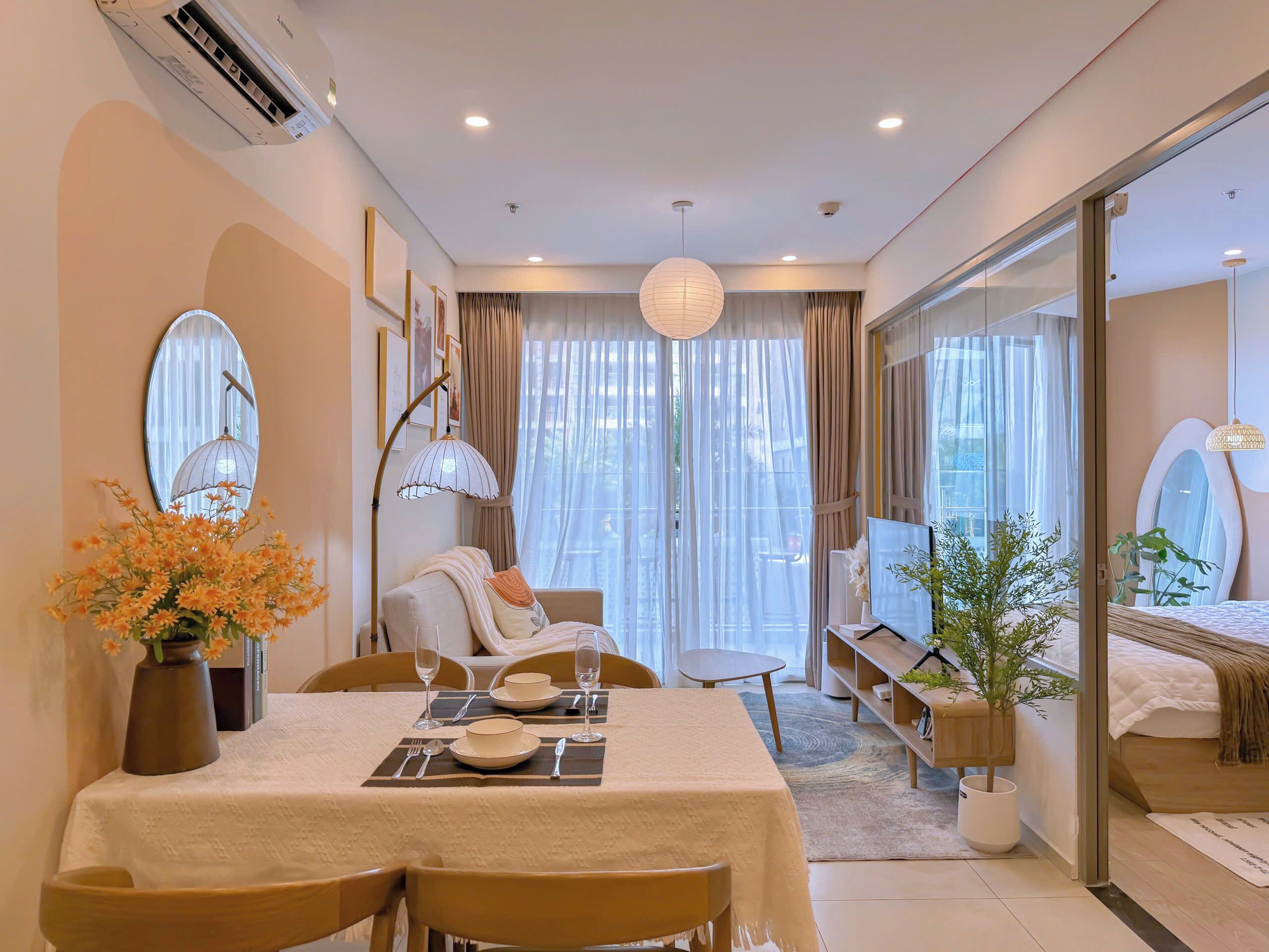 Una habitación de hotel moderna con zona de comedor, sofá, un gran ventanal con cortinas y cama con vistas.