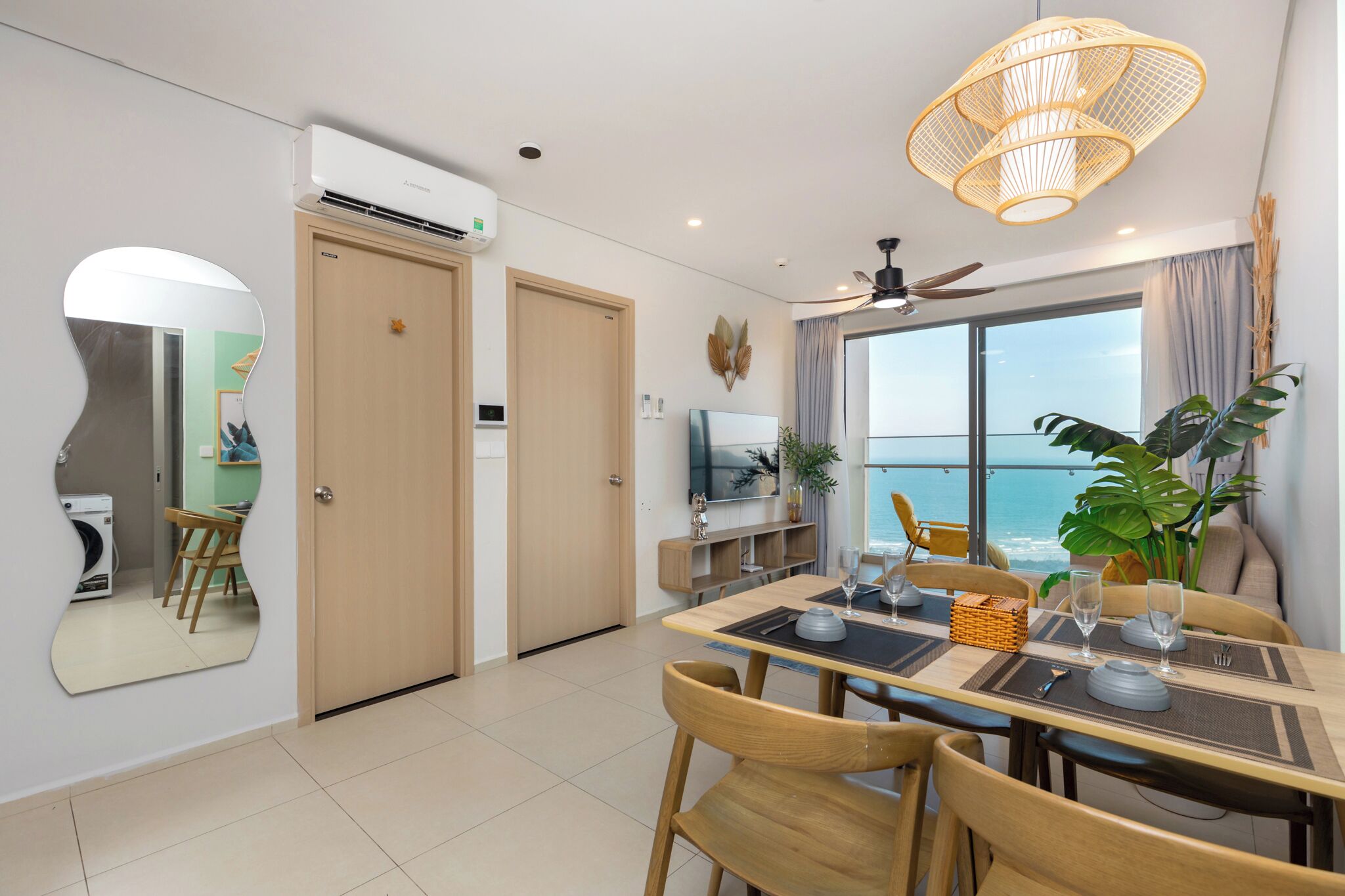A dining area with a view of the ocean, a ceiling fan, and a large mirror on the wall.