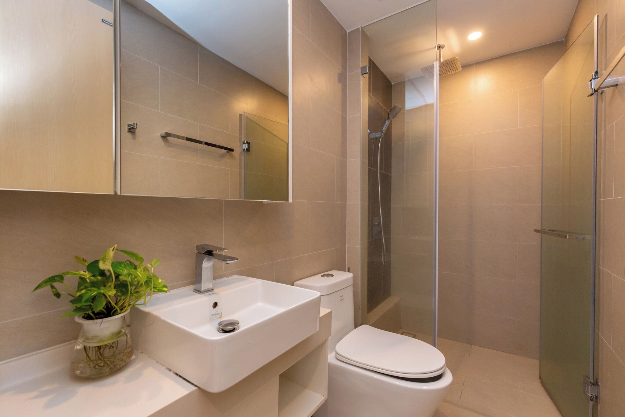 Un baño moderno con lavabo, inodoro y ducha con cerramiento de vidrio.