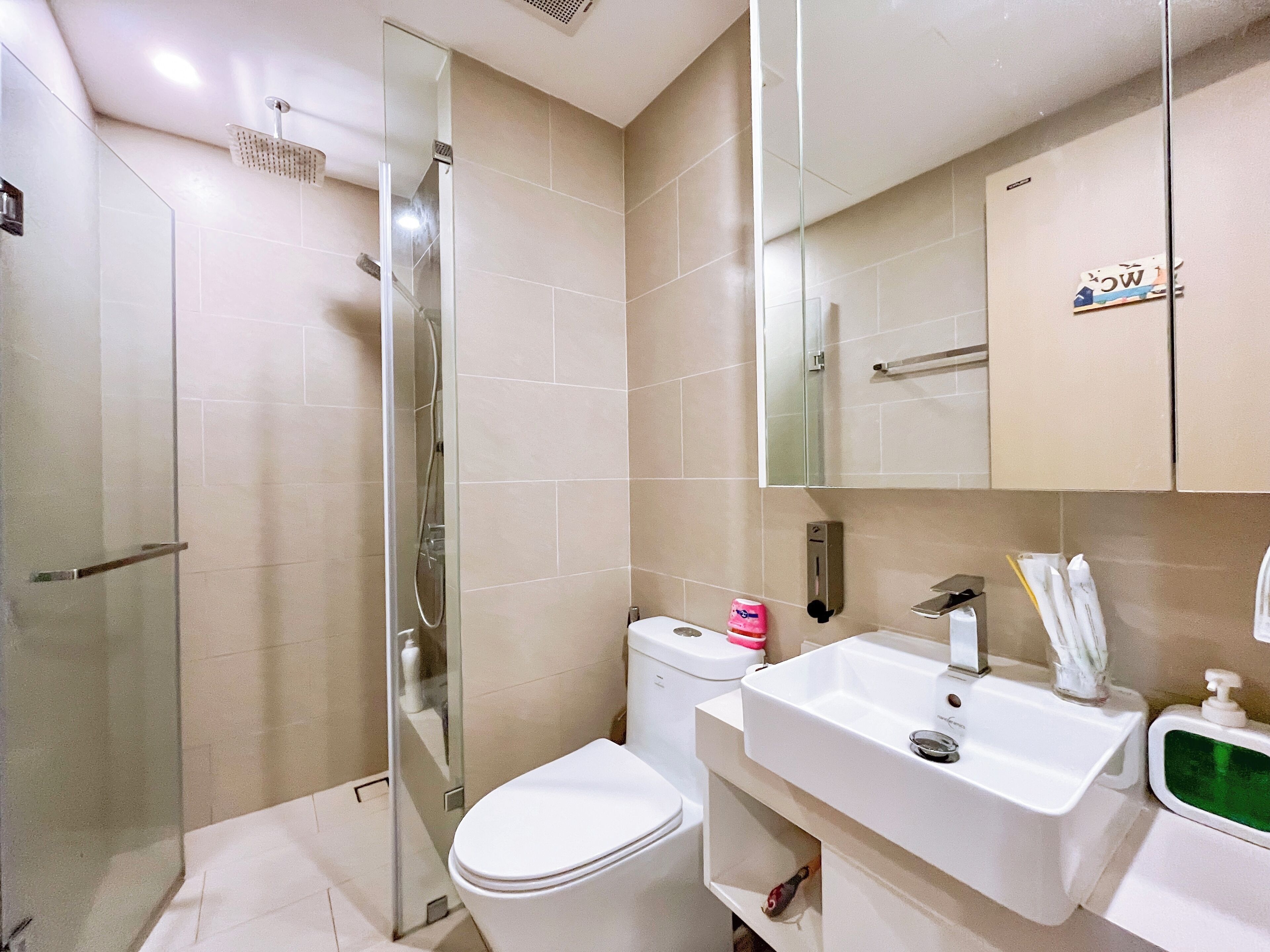 Un bagno moderno con doccia vetrata, un water bianco e un lavabo con specchio sopra.