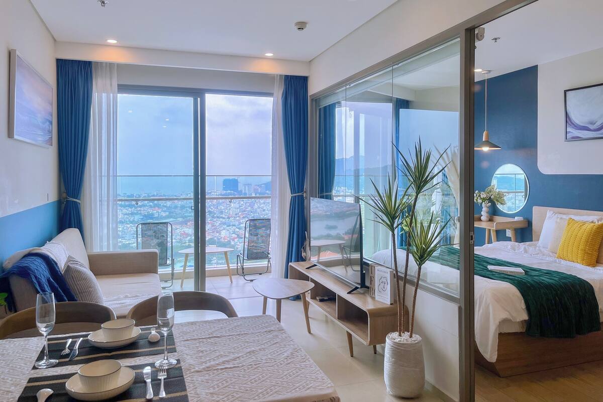 Una habitación de hotel moderna con balcón, zona de comedor y cama con vistas.