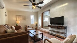 Un salon équipé d’un ventilateur de plafond, d’un téléviseur à écran plat, d’une table basse et d’un canapé.