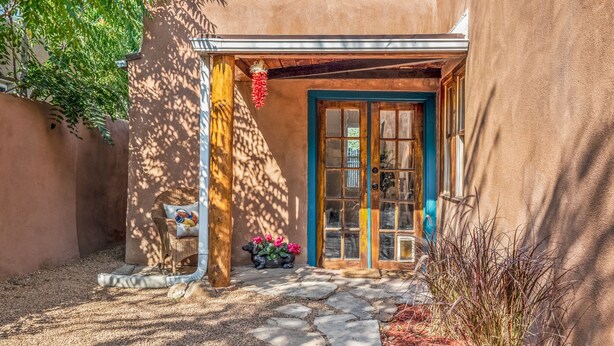 Un bâtiment rustique, avec un chemin de pierre menant à une porte en bois bordée de bleu.