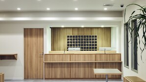A reception area with a wooden counter, a computer, and a plant. - YOU STYLE HOTEL MATE (Kagoshima)