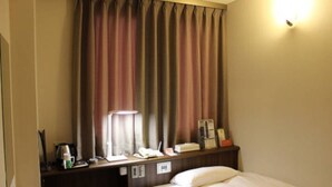 A hotel room with a bed, a desk with a telephone, a lamp, and a small cabinet. - YOU STYLE HOTEL MATE (Kagoshima)