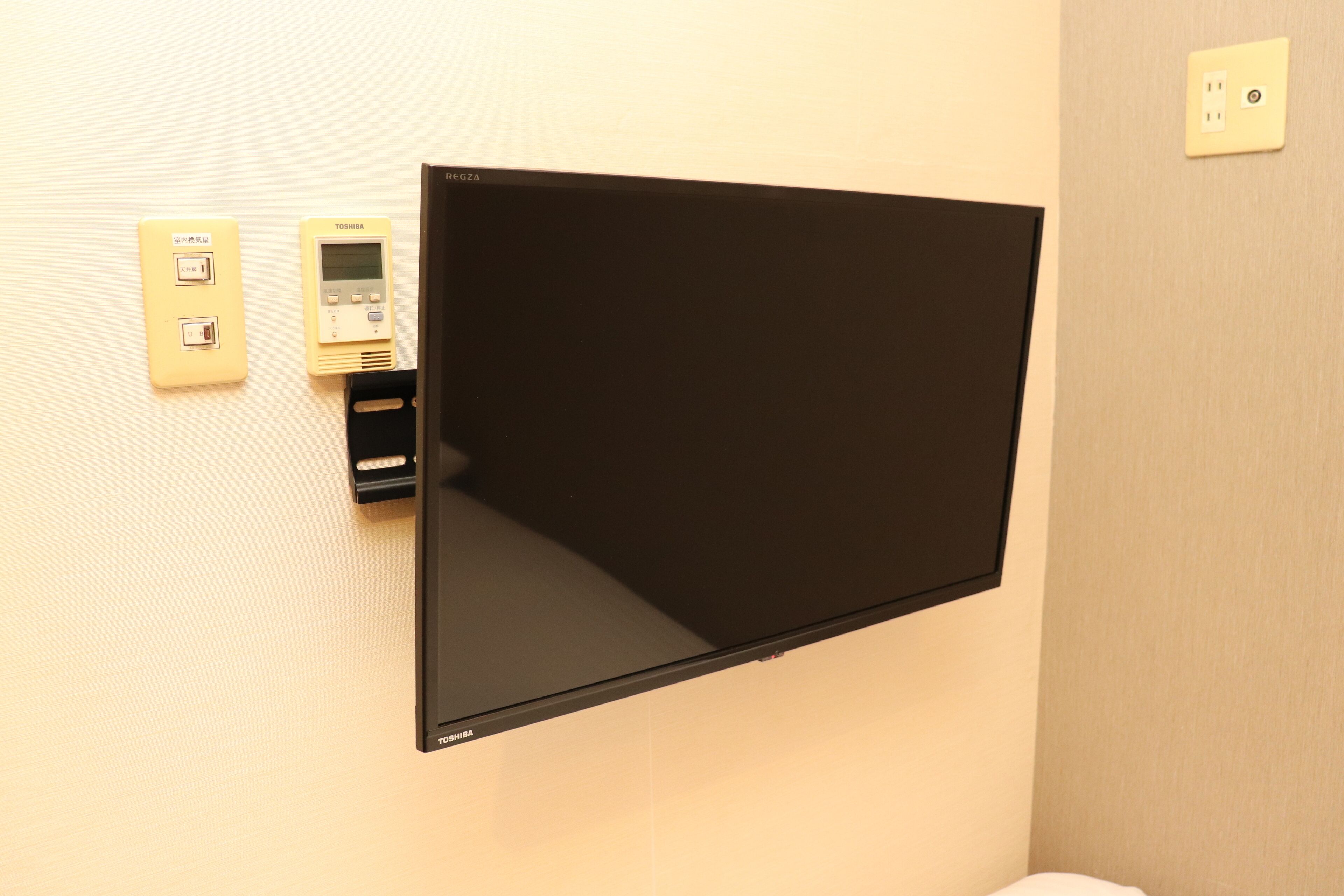 Televisor de pared con control remoto y toma de corriente.