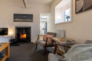 A cozy living room with a fireplace, comfortable seating, a television, and a bookshelf.