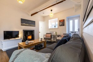 Una sala de estar con chimenea, televisor, sofá y mesa de centro.