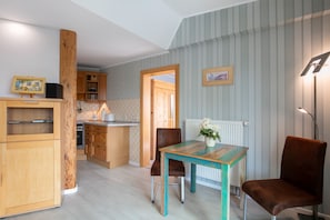 Eine Küche mit Holzausstattung, einem Esstisch mit Stühlen, einem Heizkörper und einem gerahmten Bild an der Wand.