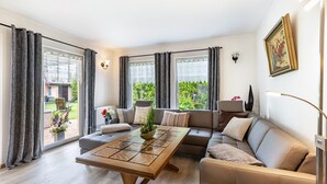A modern living room with a sofa, a coffee table, and a view of the outdoors. - Holiday Home 'Ferienhaus 75 Qm, 1 Schlafzimmer' with Private Terrace, Shared Garden and Wi-Fi (Neuruppin)