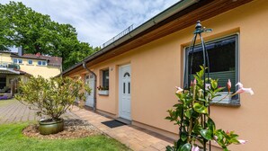 A building with a door, windows, and a small garden area with a potted plant. - Holiday Home 'Ferienhaus 75 Qm, 1 Schlafzimmer' with Private Terrace, Shared Garden and Wi-Fi (Neuruppin)