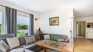 A modern living room with a sectional sofa, a coffee table, and a painting on the wall. - Holiday Home 'Ferienhaus 75 Qm, 1 Schlafzimmer' with Private Terrace, Shared Garden and Wi-Fi (Neuruppin)
