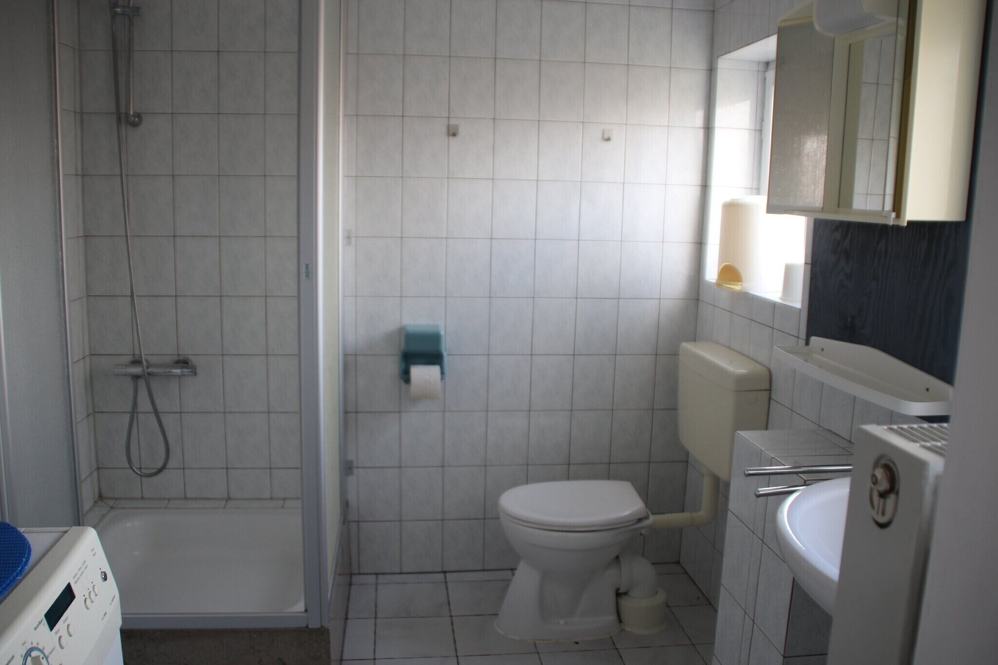 Et badeværelse med brusebad, toilet, vask og spejl.