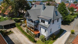 Een tweelaags huis met een schuin dak, een garage en een kleine tuin.