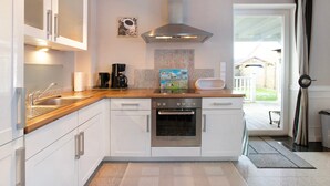 A modern kitchen with white cabinets, a stainless steel range hood, a built-in oven, and a wooden countertop. - Apartment 'Wendtlandt' with Private Terrace and Wi-Fi (Kappeln)