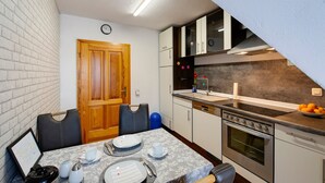 Cocina compacta con zona de comedor, que incluye una puerta de madera, un reloj, una estufa y un lavamanos.