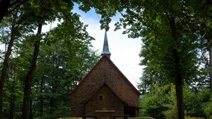 A stone church with a pointed steeple, surrounded by trees. - Holiday Apartment Odenwald with Terrace and Wi-Fi (Wald-Michelbach)