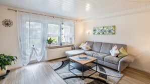 A living room with a sofa, coffee table, and a potted plant. - Holiday Apartment Odenwald with Terrace and Wi-Fi (Wald-Michelbach)