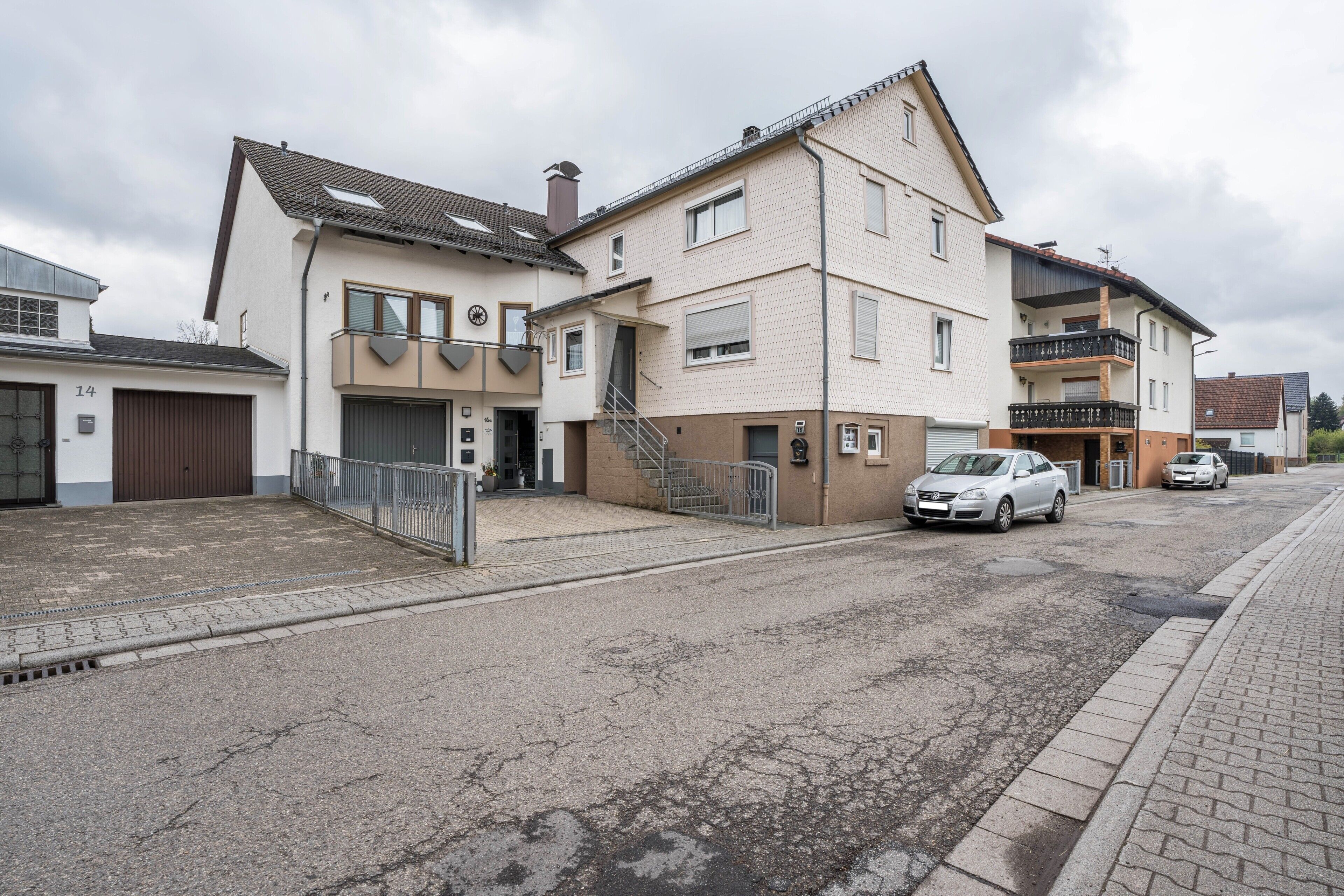 A residential street with houses, a garage, and a staircase leading to a second floor.