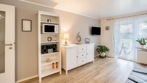 A room with a white cabinet, a television, a potted plant, and a window with curtains. - Holiday Apartment Odenwald with Terrace and Wi-Fi (Wald-Michelbach)