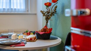 Ein Esstisch ist gedeckt mit Tellern, Gläsern, einem Brotkorb und einer Blumenvase.