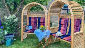 Eine Holzwilabe mit gepolsterten Sitzgelegenheiten und einem Tisch mit Spitzenbettwäsche.
