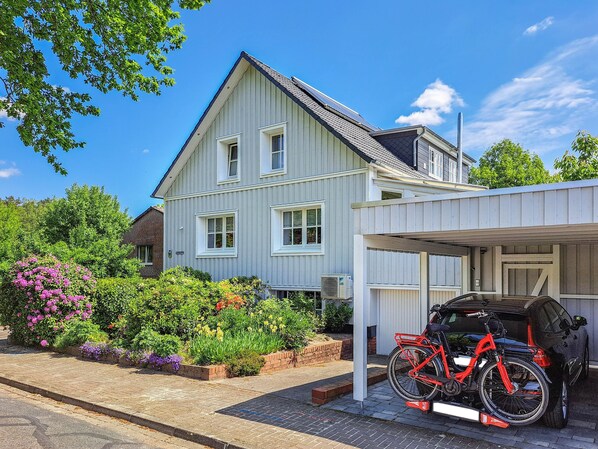 A two-story house with a covered garage, a bicycle, and a barbecue grill.